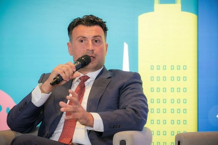Vlad Musteață speaking into a microphone during the panel on the residential market's future.