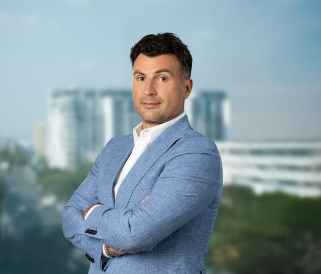 Vlad Musteață, portrait with arms crossed and buildings in the background.
